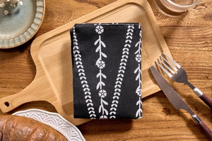 Macro view of black linen napkin with white floral pattern and fine stitched edges