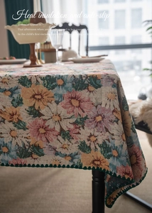 Macro detail of French vintage floral jacquard tablecloth with green wavy pom-pom trim