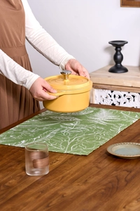 Close-up of bright yellow enamel cast iron pot with metal lid handle on a home dining table