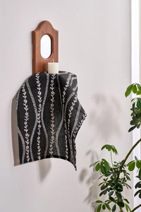 Detail of Nordic style black fabric napkin with white floral pattern hanging on wood