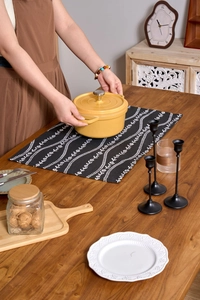 Detail view of a yellow enamel cast iron pot on a black floral table runner decoration