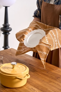 Detail of floral printed cotton tea towel being used with a ceramic plate and pot