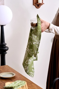 Close-up of green cotton linen napkin with white leaf print used for drying glassware