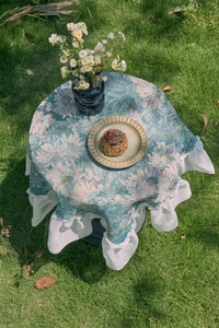 Close-up of vintage floral tablecloth with elegant white lace ruffles and bow detail