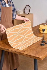 Detail of floral orange cotton linen napkin held over a cozy rustic wooden table