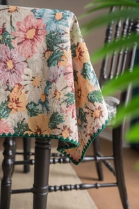 Detail of vintage floral jacquard tablecloth with thick texture and green wavy scalloped edges