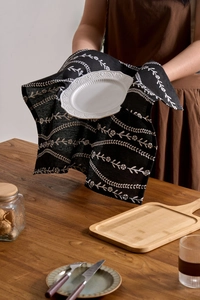 Close-up of black floral fabric napkin placed under a white embossed ceramic plate