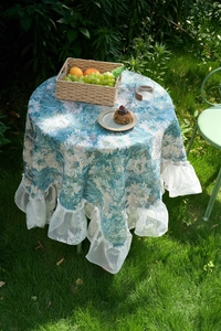 Detail of blue floral tablecloth with elegant white lace ruffle edges on outdoor lawn