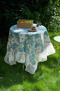 Close-up of blue floral jacquard tablecloth with elegant white lace ruffled edges