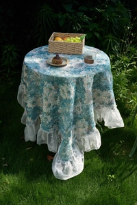 Detail of round floral tablecloth with wide white lace edges for outdoor tea time