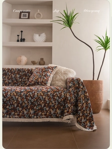 Detailansicht der Jacquard-Sofadecke mit Blumenmuster und Fransen sowie Kissen