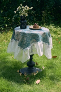 Detailed close-up of blue Monet floral jacquard tablecloth with white lace ruffle edge