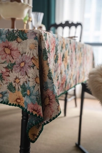 Detailed close-up of French floral jacquard tablecloth with green scalloped edges