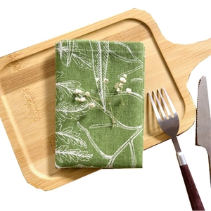 Green French pastoral cloth napkin with white leaf prints on a rustic wooden tray