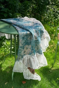 Close-up of jacquard floral tablecloth with elegant white lace ruffle edges in a garden