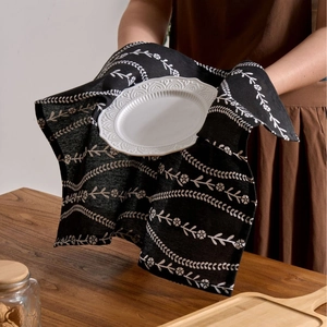 Nordic style black cotton napkin with white floral print held by hand over table