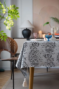 Detail of gray damascus patterned tablecloth featuring elegant corner tassel decorations