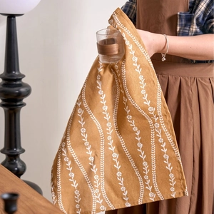 American pastoral ginger yellow floral cotton linen napkin held by a person at a wooden table