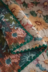 Macro detail of French vintage floral jacquard tablecloth with green scalloped crochet edge