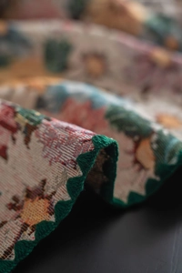 Macro detail of French vintage tablecloth with green scalloped edges and floral jacquard