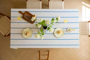 Close-up of linen fabric texture with blue geometric diamond embroidery on rectangular tablecloth