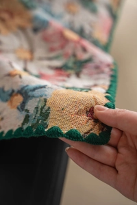 Close-up of jacquard floral tablecloth showing thick texture and green scalloped edges