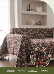 Détail de la housse de canapé fleurie montrant le tissu tissé épais et les pompons blancs