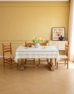 Close-up of beige linen tablecloth with blue stripes and white tassel fringe detailing