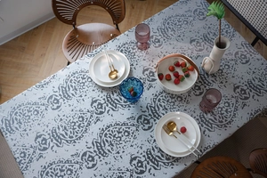 Detail of grey jacquard tablecloth featuring damask patterns and elegant fringe tassels