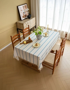 Detail of white linen tablecloth featuring blue vertical stripes and delicate fringe edges