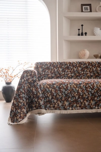 Detail der vintage Jacquard Sofa-Überwurfdecke mit dunklem Blumenmuster und weißen Fransen