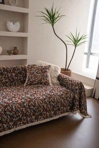 Detailansicht des Sofabezugs mit Vintage-Blumenmuster und eleganten weißen Quastenfransen