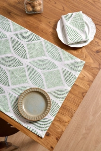 Close-up of green leaf pattern table runner and napkin set on a rustic wooden dining table