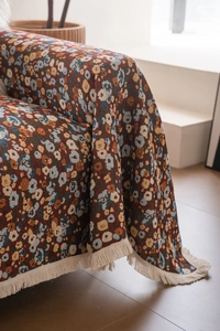 Nahaufnahme der Vintage-Strick-Sofadecke mit Blumenmuster und cremefarbenen Fransen