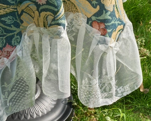 Close-up of vintage floral jacquard tablecloth featuring elegant white lace ruffle edges