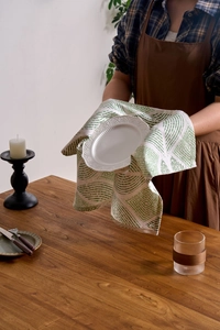 Close-up of a Nordic style white linen napkin with green geometric diamond patterns