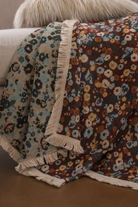 Detailansicht der gewebten Decke mit Blumenmustern, Leoparden-Prints und beigen Quasten