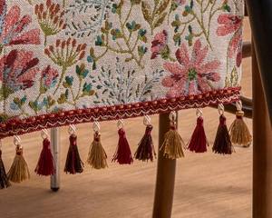 Close-up of floral jacquard table runner with decorative red and brown fringe tassels