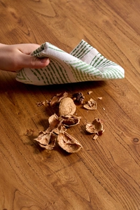 Detail of green striped linen napkin cleaning walnut shells on a solid wood table
