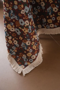 Nahaufnahme der dicken Jacquard-Sofadecke mit Blumenmuster und hellen Fransen