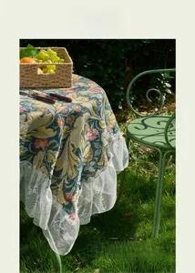 Detail of floral jacquard tablecloth with white lace ruffle edges on garden table