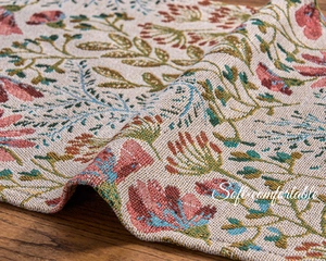 Detail of French floral jacquard fabric with woven red flowers on a wooden table