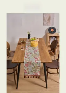 Detailed view of pink floral table runner with colorful tassels and jacquard texture