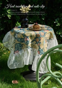 Detail of floral tablecloth with white lace edges on outdoor garden tea table