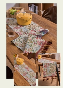 Detail of French country style floral jacquard table runner with decorative tassels