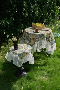 Detail of vintage green floral jacquard tablecloth with elegant white lace ruffled edges