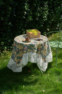 Detail of floral jacquard tablecloth with white lace ruffle edge on a garden table