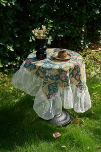 Detailed close-up of retro floral jacquard fabric with elegant white lace ruffle edges