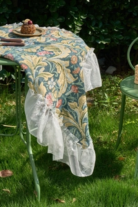 Detail of vintage floral jacquard table runner with delicate white lace ruffled edges