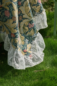 Macro detail of vintage floral jacquard fabric with delicate white lace ruffled edge